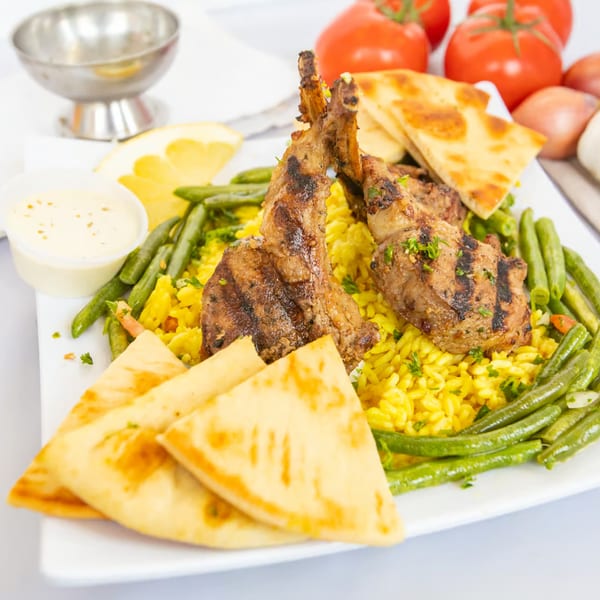 Grilled lamb chops on yellow rice with green beans and pita bread, served at The Fat Greek.